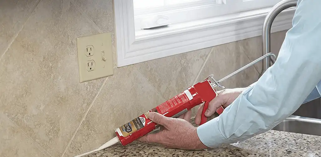 Handyman applying caulk along a kitchen backsplash and countertop seam in El Paso, TX