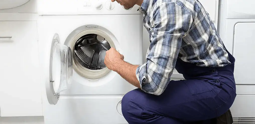 Handyman inspecting a dryer drum and internal parts for repair in El Paso, TX