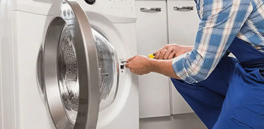 Handyman repairing a clothes dryer and checking electrical connections in El Paso, TX