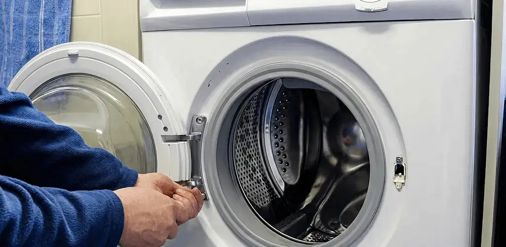Washing machine repair handyman checking a front-load washer door and latch in El Paso, TX