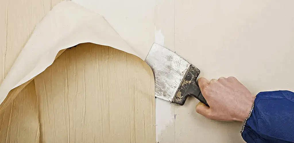Handyman removing wallpaper with a scraper for wall preparation in El Paso, TX