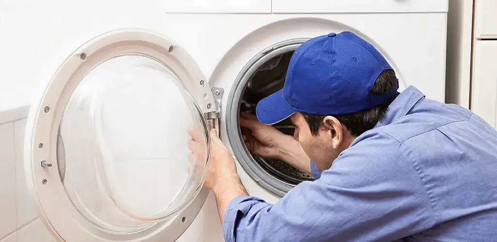 Washing machine repair handyman inspecting a front-load washer drum in El Paso, TX