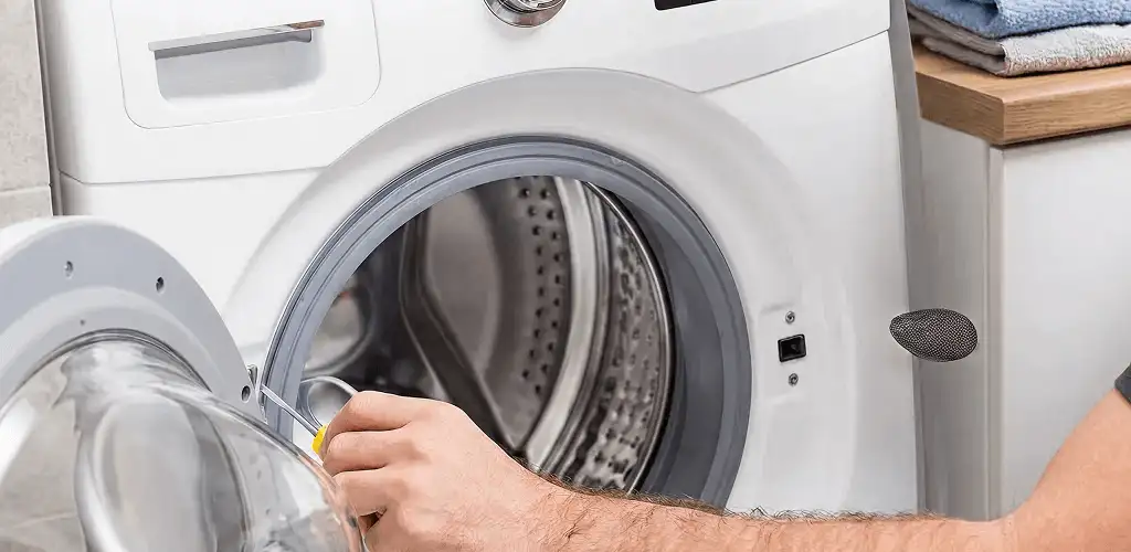 Handyman repairing a front-load washing machine and inspecting the drum in El Paso, TX