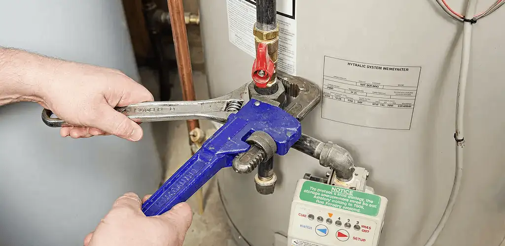 Water heater repair technician tightening the shutoff valve and supply line in El Paso, TX